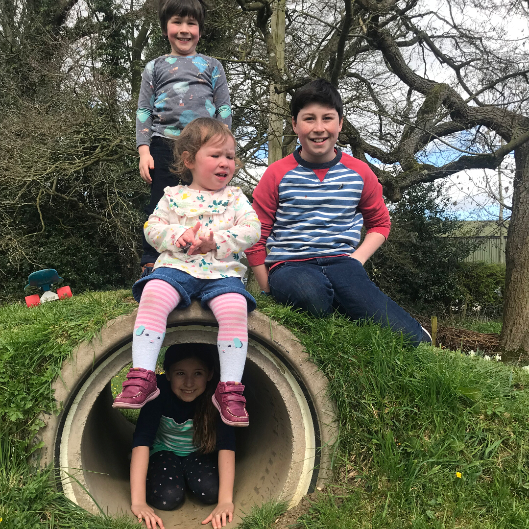 4 children say on a grass mound
