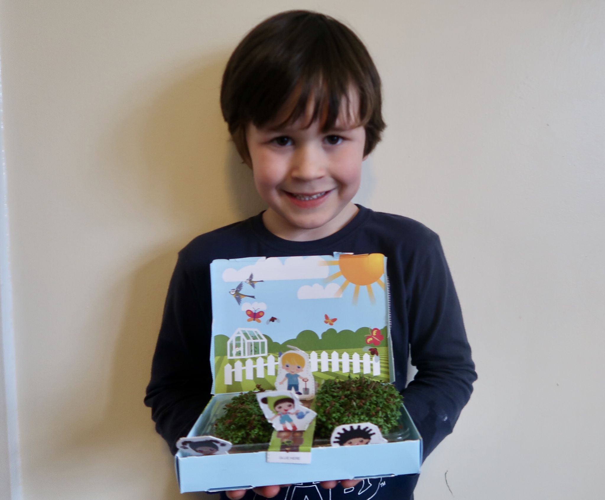 A boy holding his cress garden