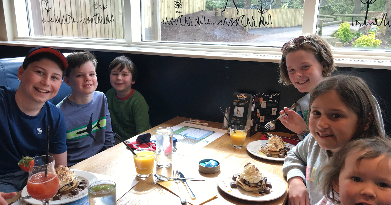6 children smiling at a cafe serving pancakes