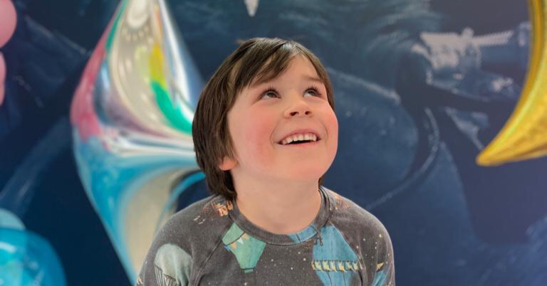 A boy looking at helium moon and stars balloons