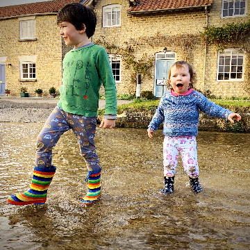 Two children paddling in the river
