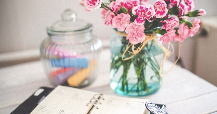 flowers in a jar and chalk in a jar with a diary 