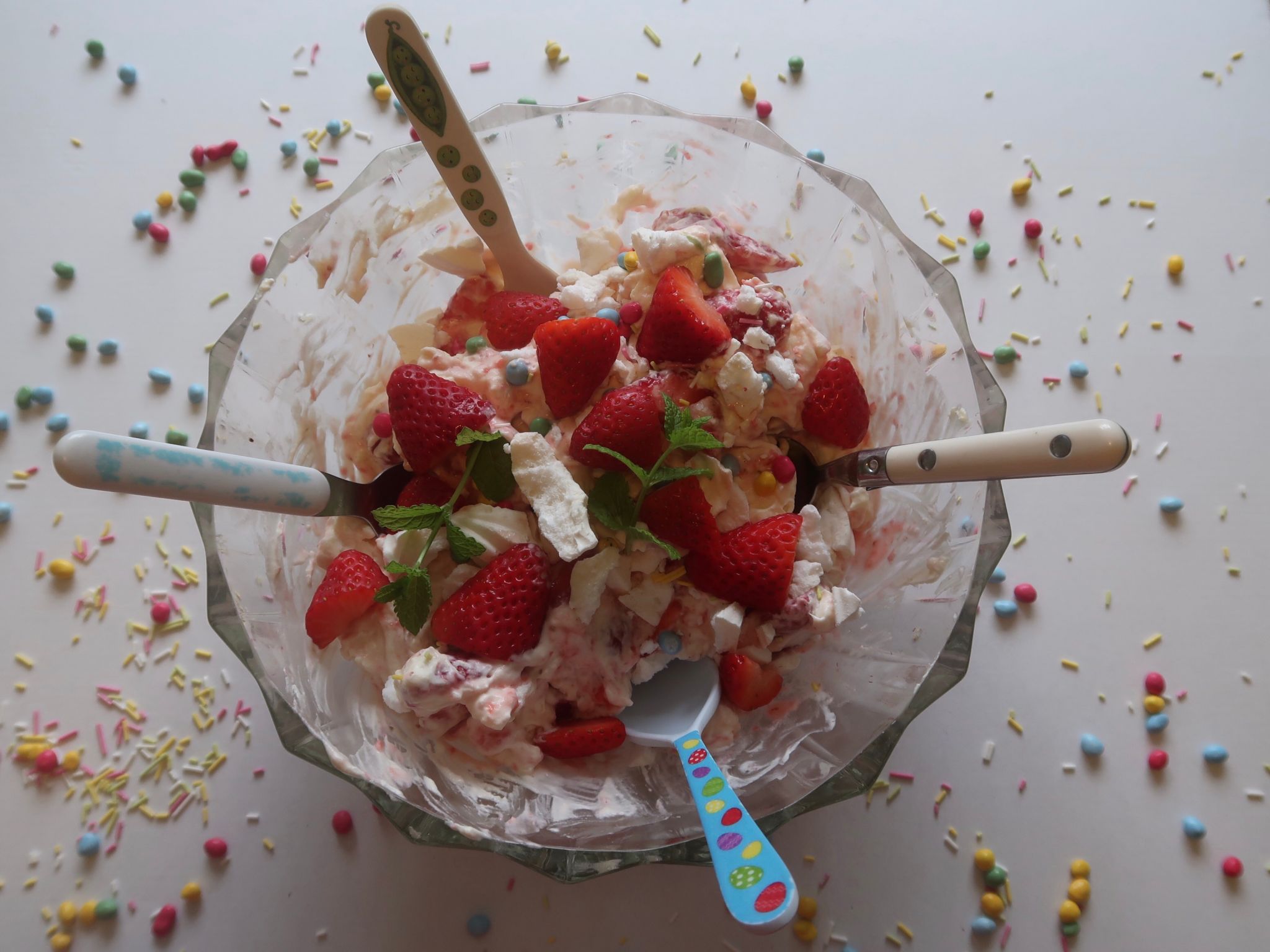 a large bowl of Eton mess with 4 small spoons in it
