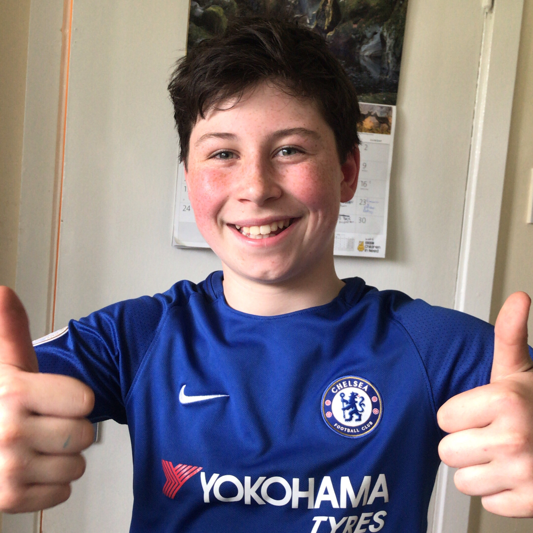 a young teenage boy smiling with his thumbs up