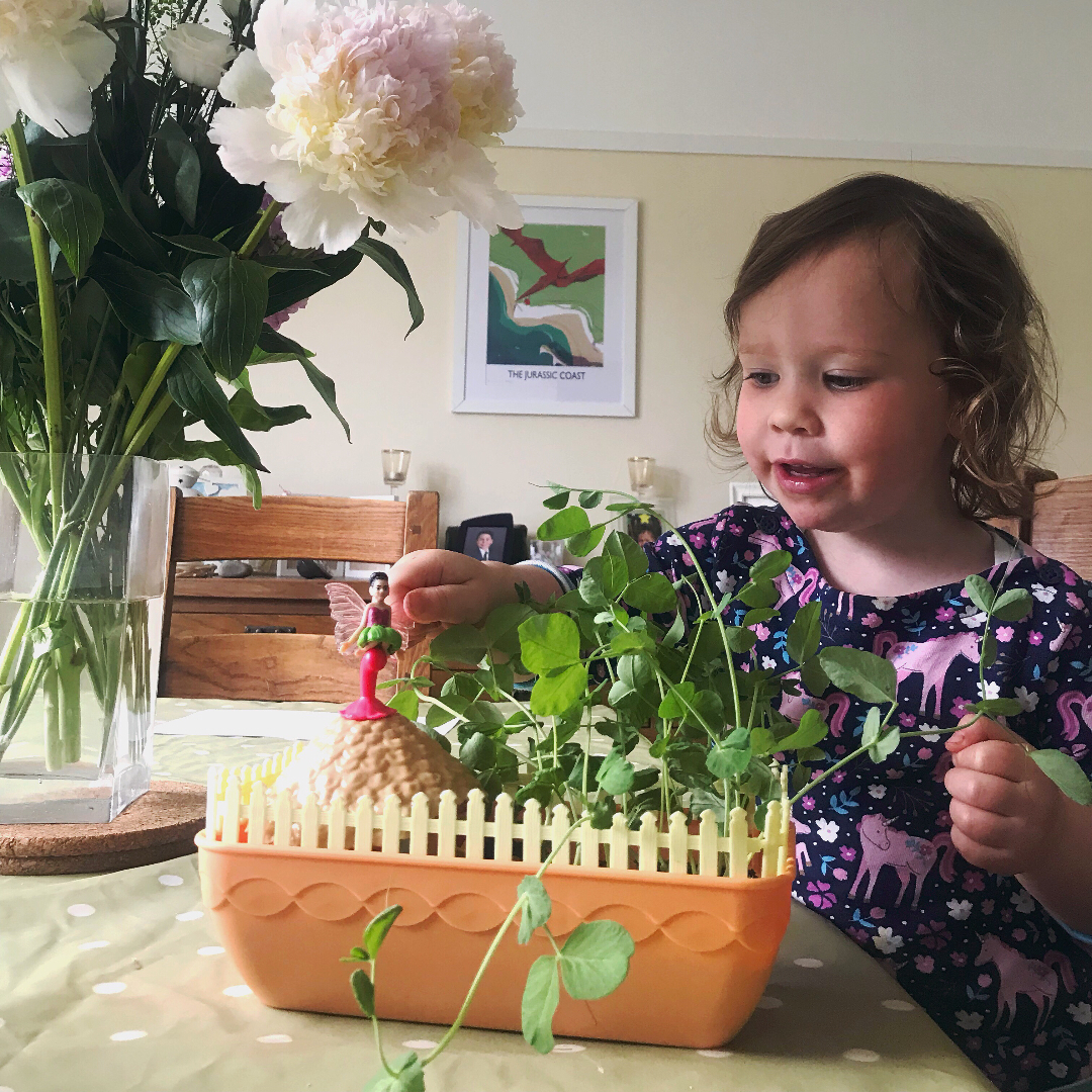 A child playing with a fairy garden and smiling sweetly