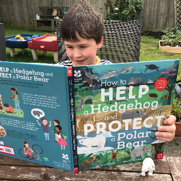 A small boy reading a book outside