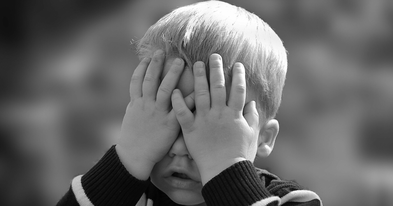 A little boy with his hands over his eyes
