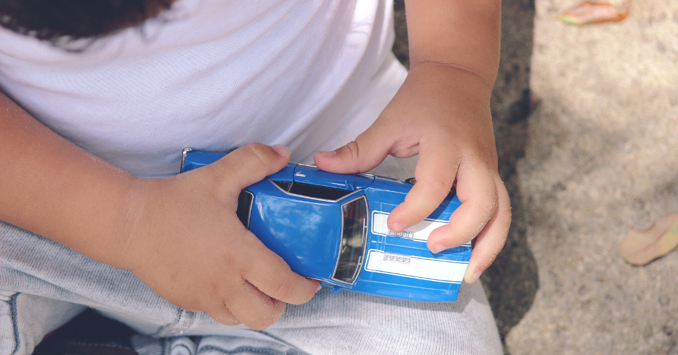 Child playing with a small car
