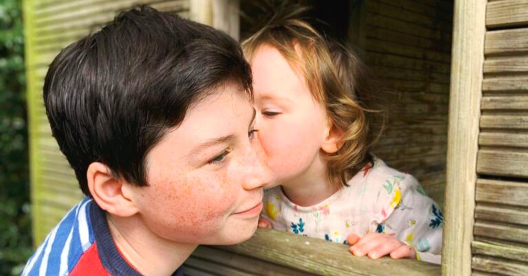 a toddler kissing her brother 
