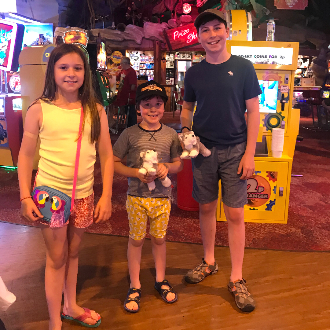 Three children posing for a photo in an arcade