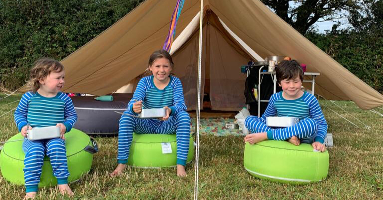 3 children sat outside a tent eating 