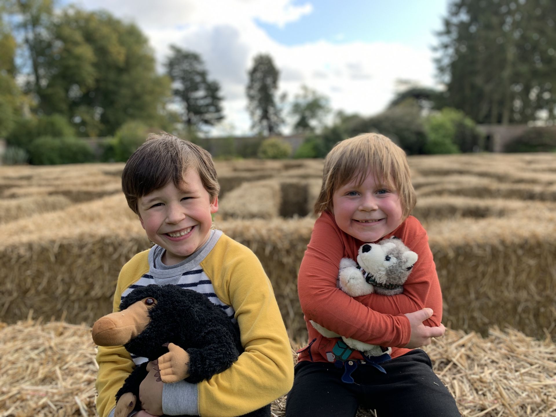 two boys cuddling teddy's on hay bales