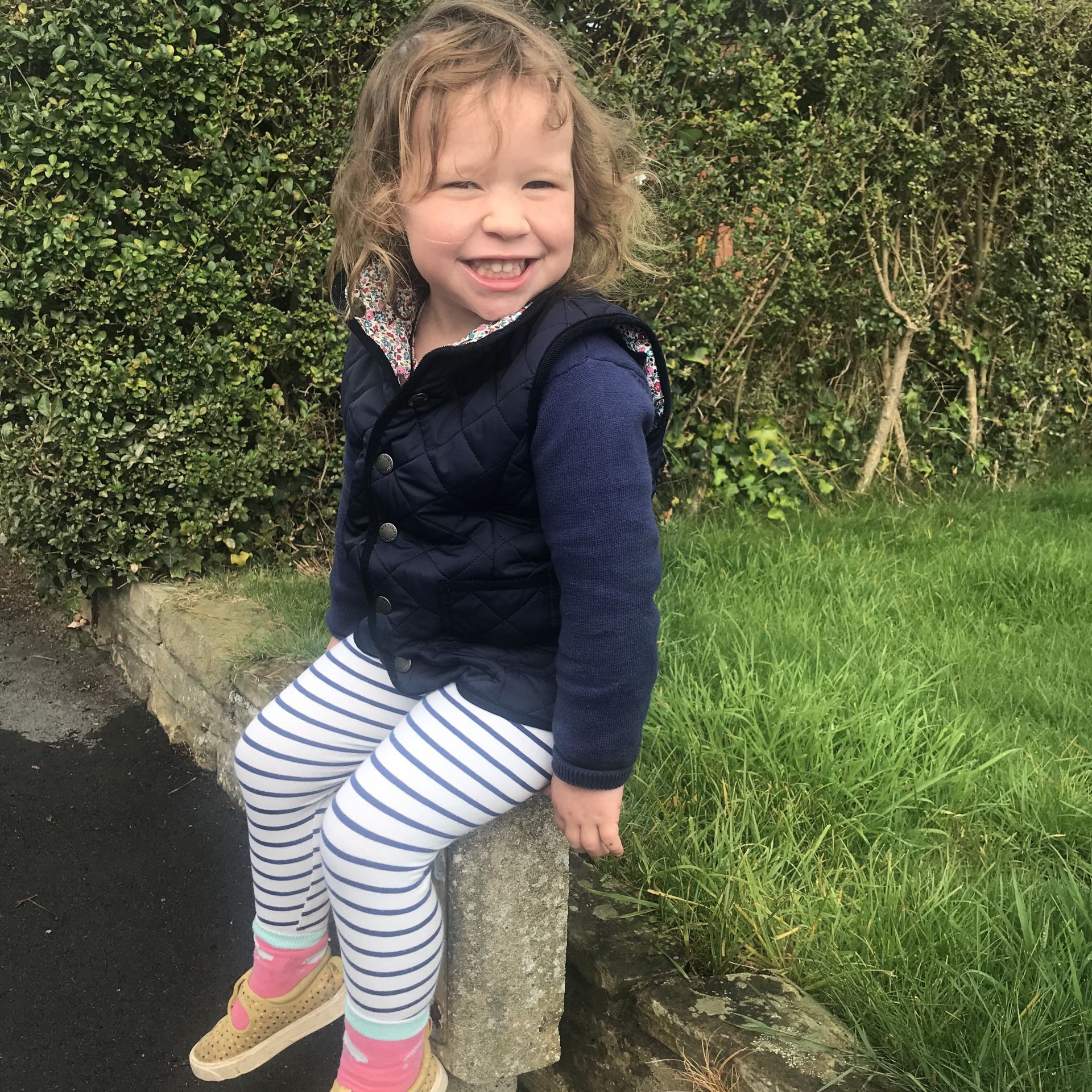 girl sat smiling on a wall