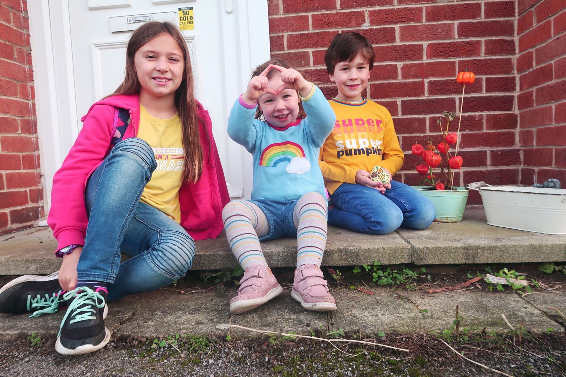3 kids sat smiling on a step