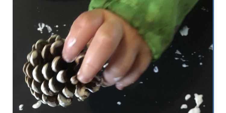 a pinecone printed in white paint for baby Christmas activities
