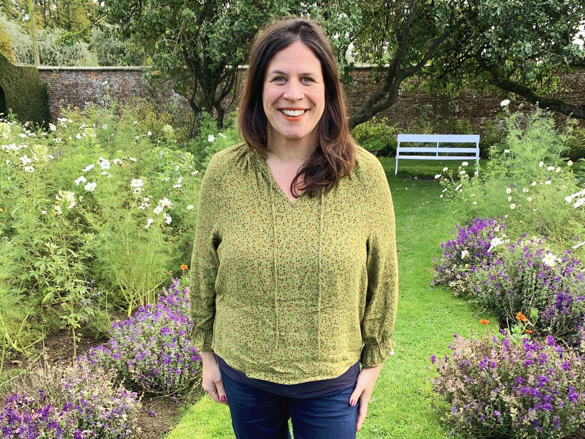 a lady posing for a picture in a garden