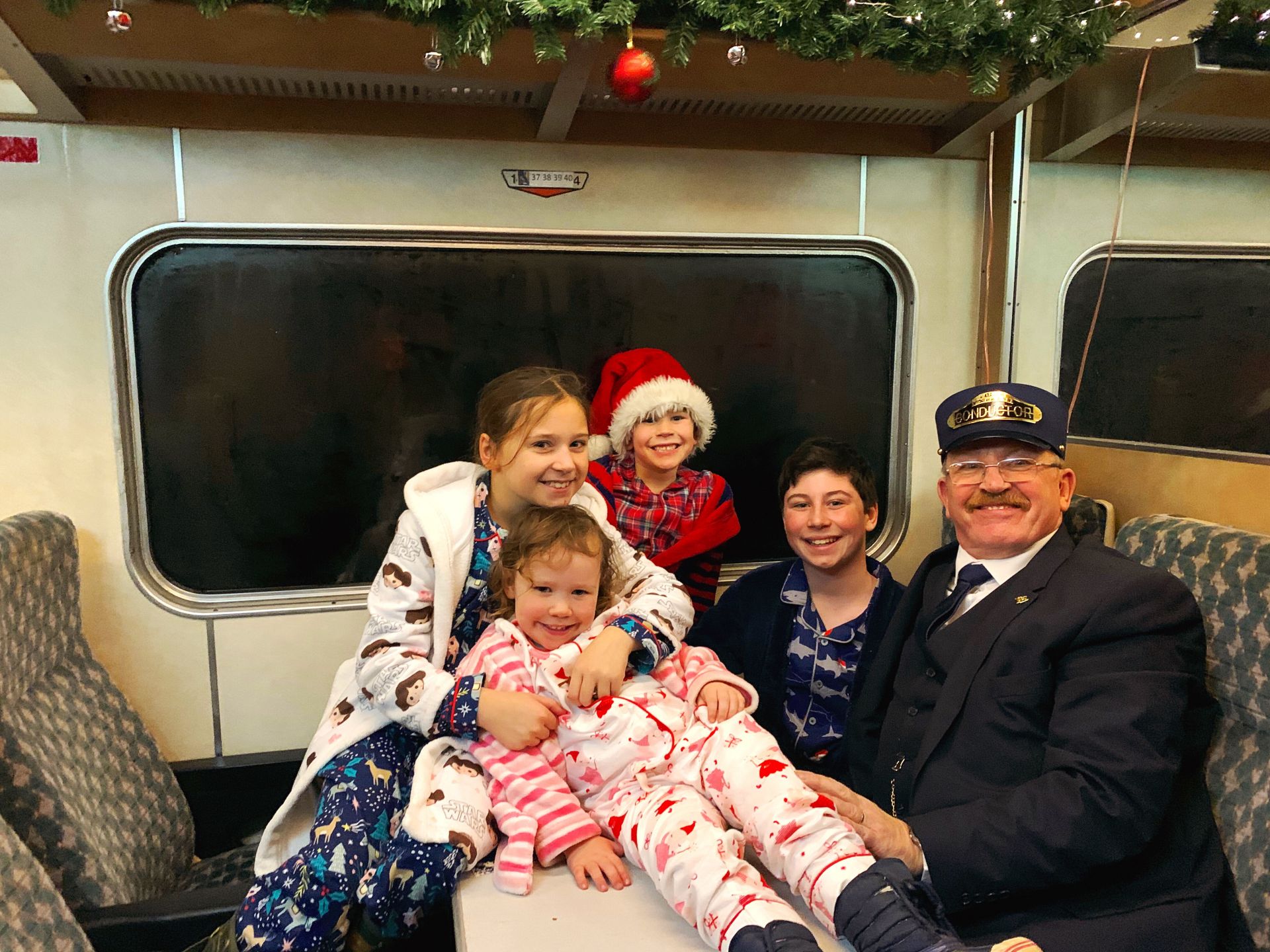 4 children posing for a picture with a train conductor