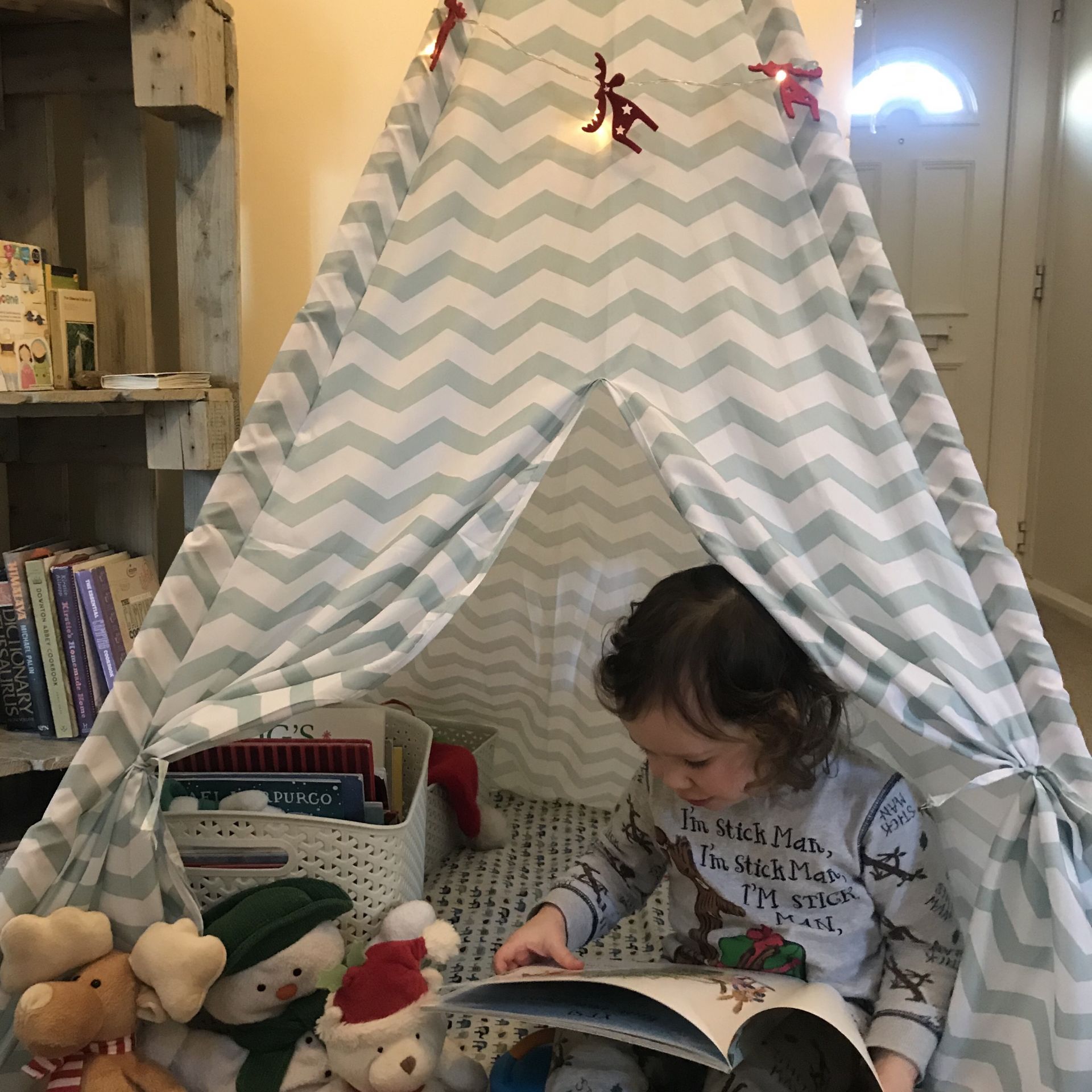 a toddler reading in a teepee 