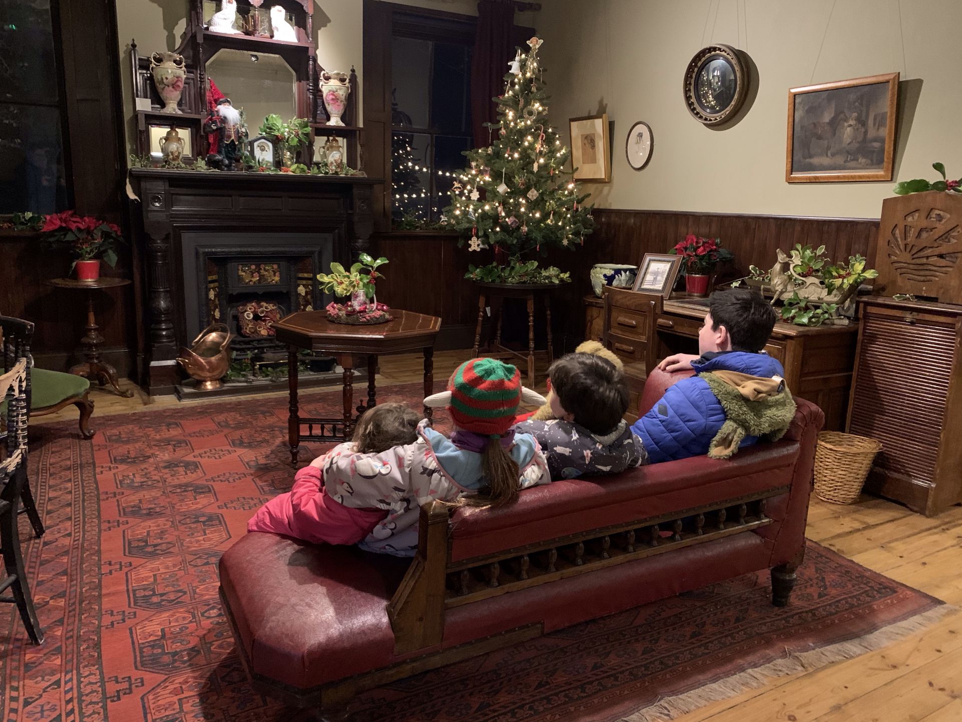 children sat on a sofa I a christmassy room