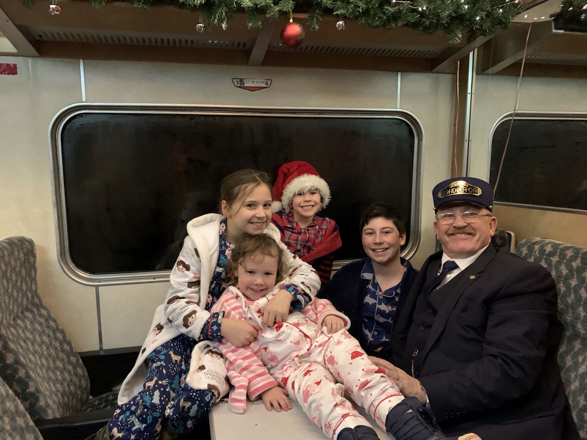 4 CHILDREN POSING FOR A PICTURE WITH TRAIN CONDUCTOR