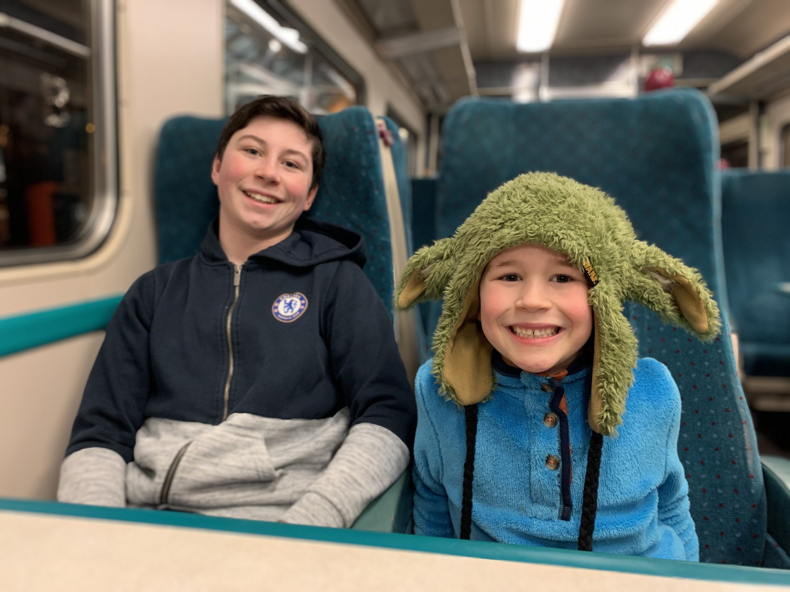 two boys sat in a train carriage posing for a photo 