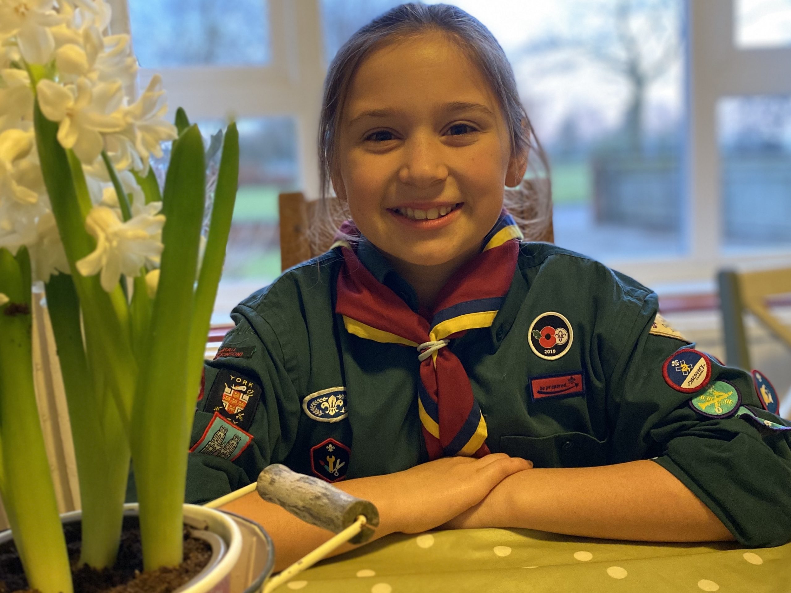 family life with a girl in scout uniform sat at the kitchen table