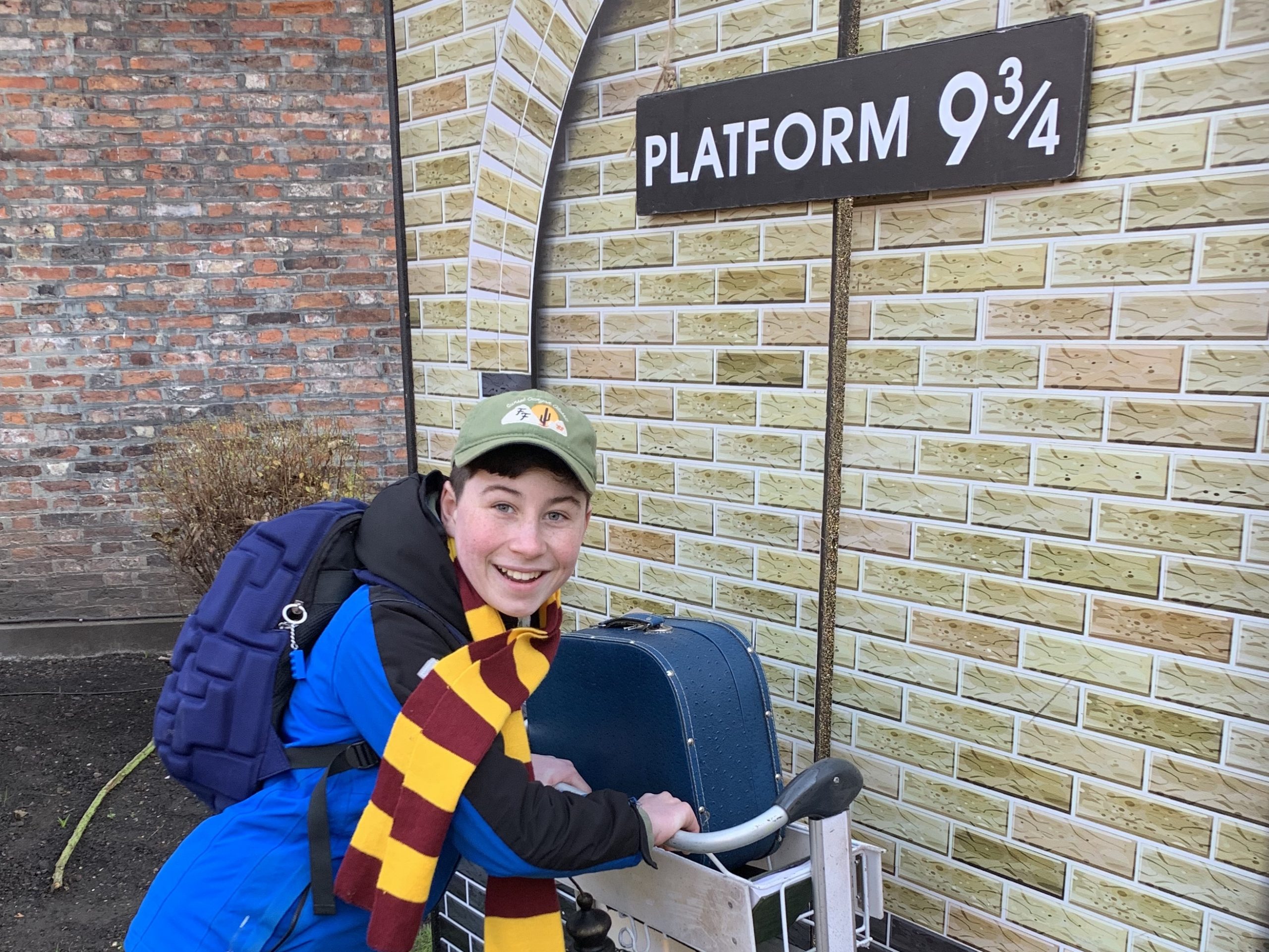 a boy running towards Hogwarts platform 9 3/4 with a trolley