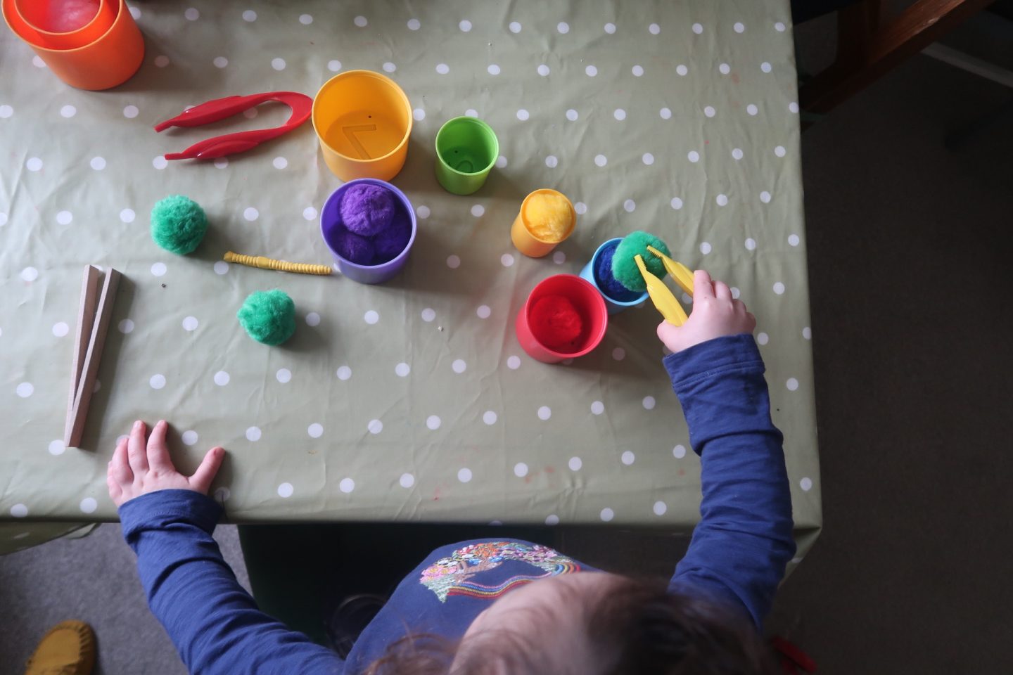 a young girl popping pom poms into stacking cups