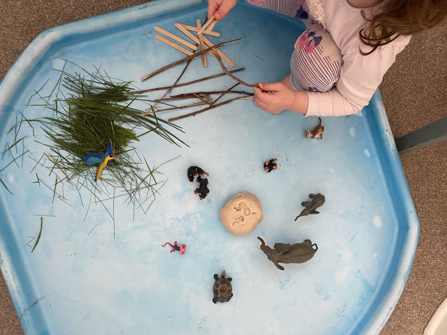 a child playing with grass and play dough 