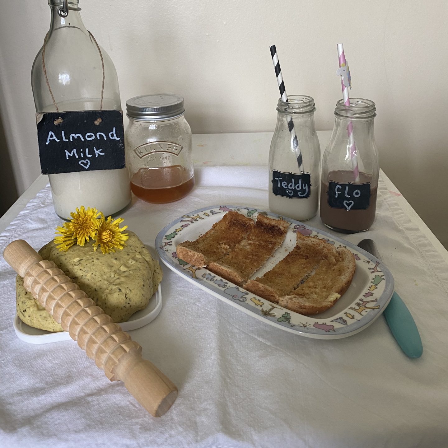 A table of self care with almond milk, toast, honey and playdough.