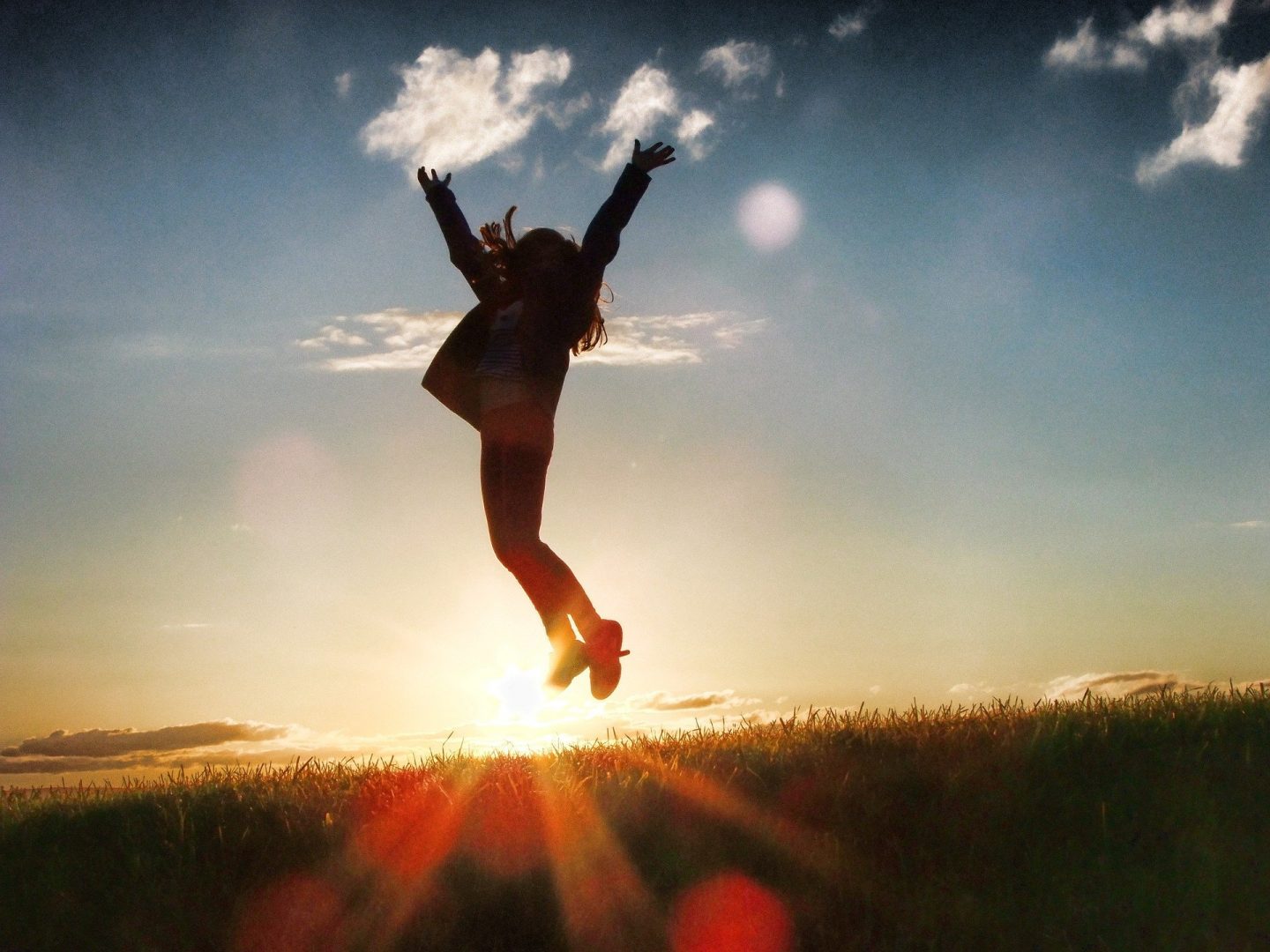 A lady jumping for joy outside in the sunset 
