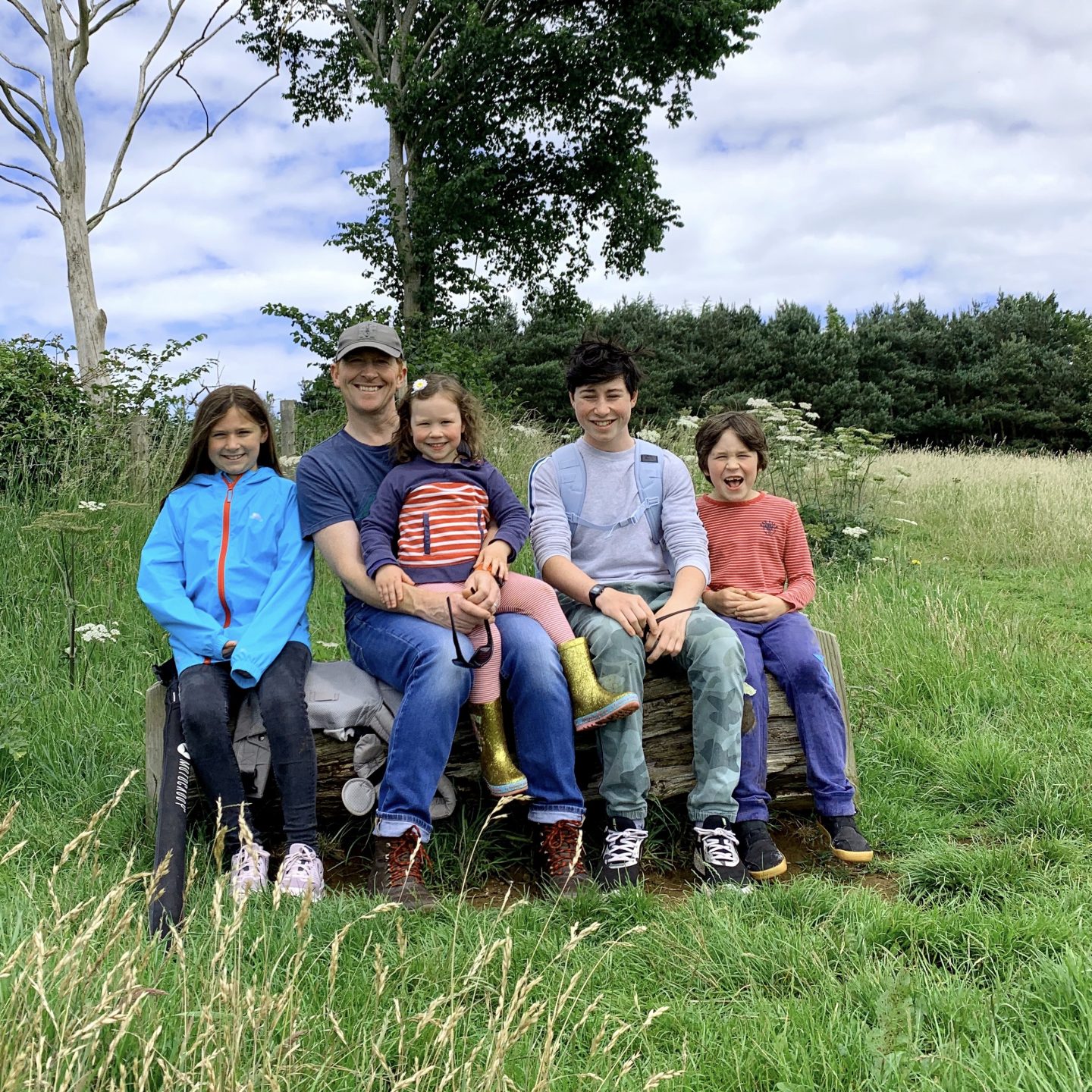 A picture of a Daddy and 4 kids on a bench smiling