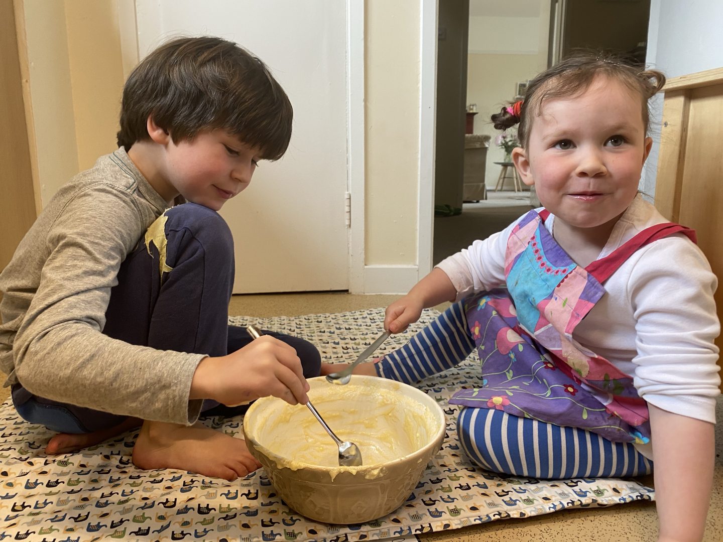 2 young children baking and  licking the bowl out