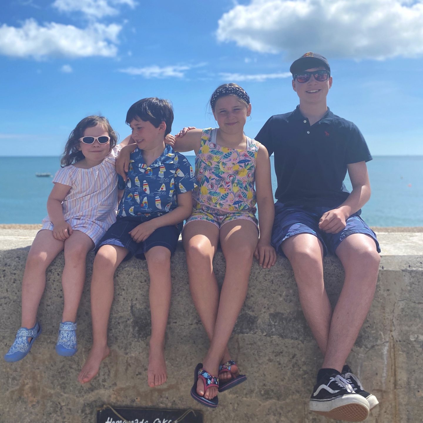 Camping in Devon with 4 kids sat on a wall having their picture taken