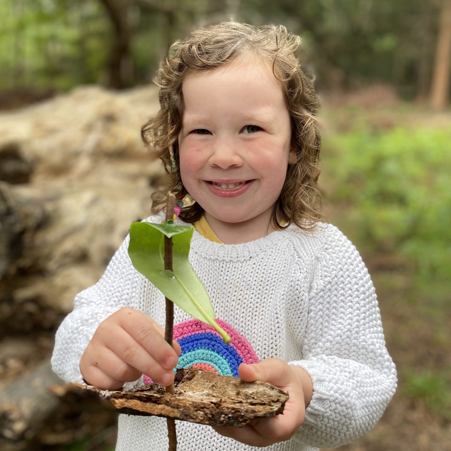 Small girl smiling with a nature boat of leaves and twigs 