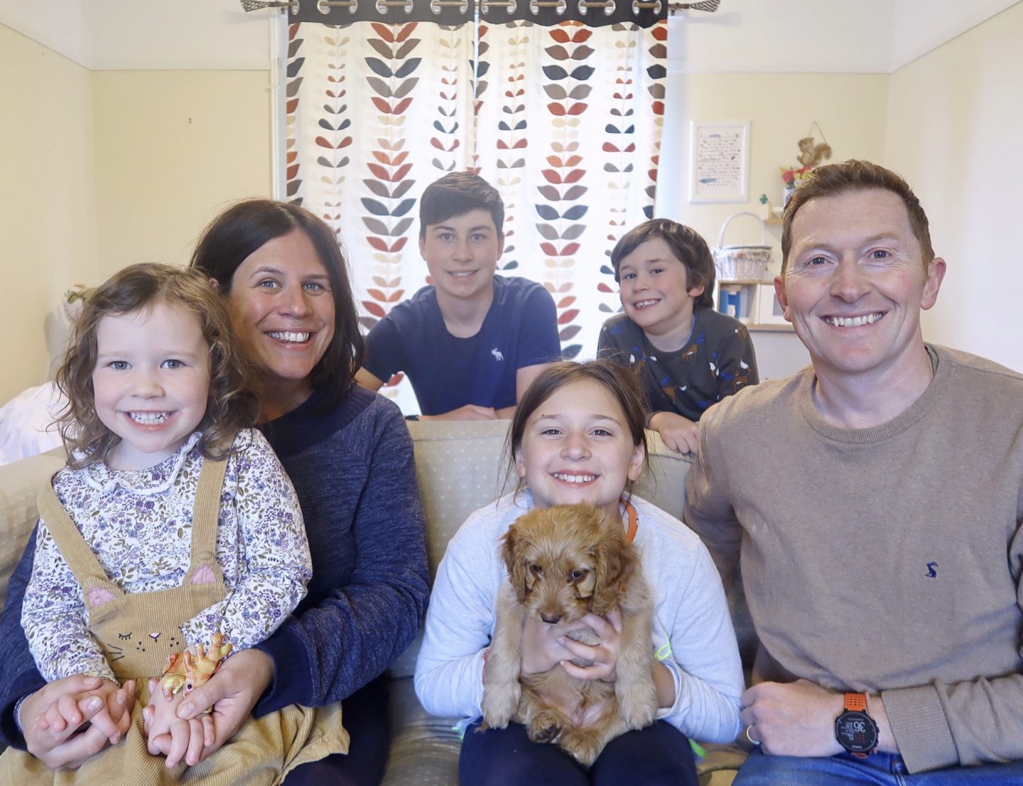 Red cockapoo with his new family having a picture