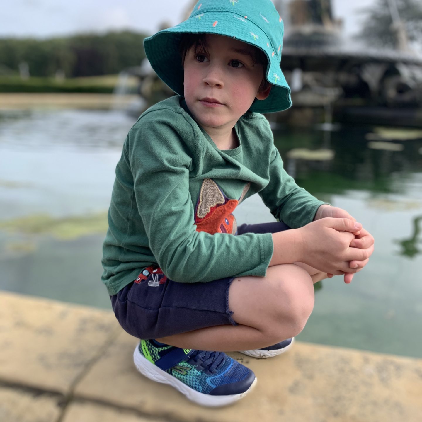A young boy sat by a fountain