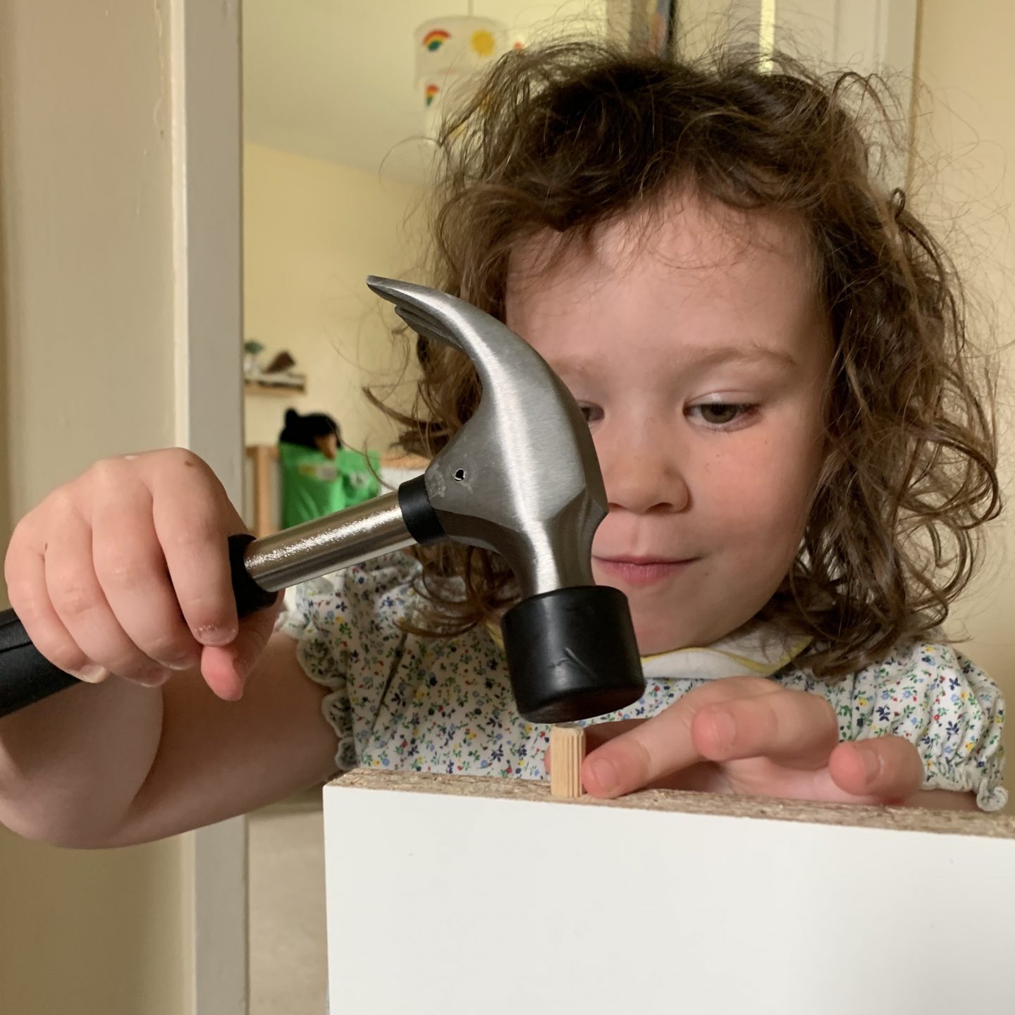 A child hammering  a nail into furniture 