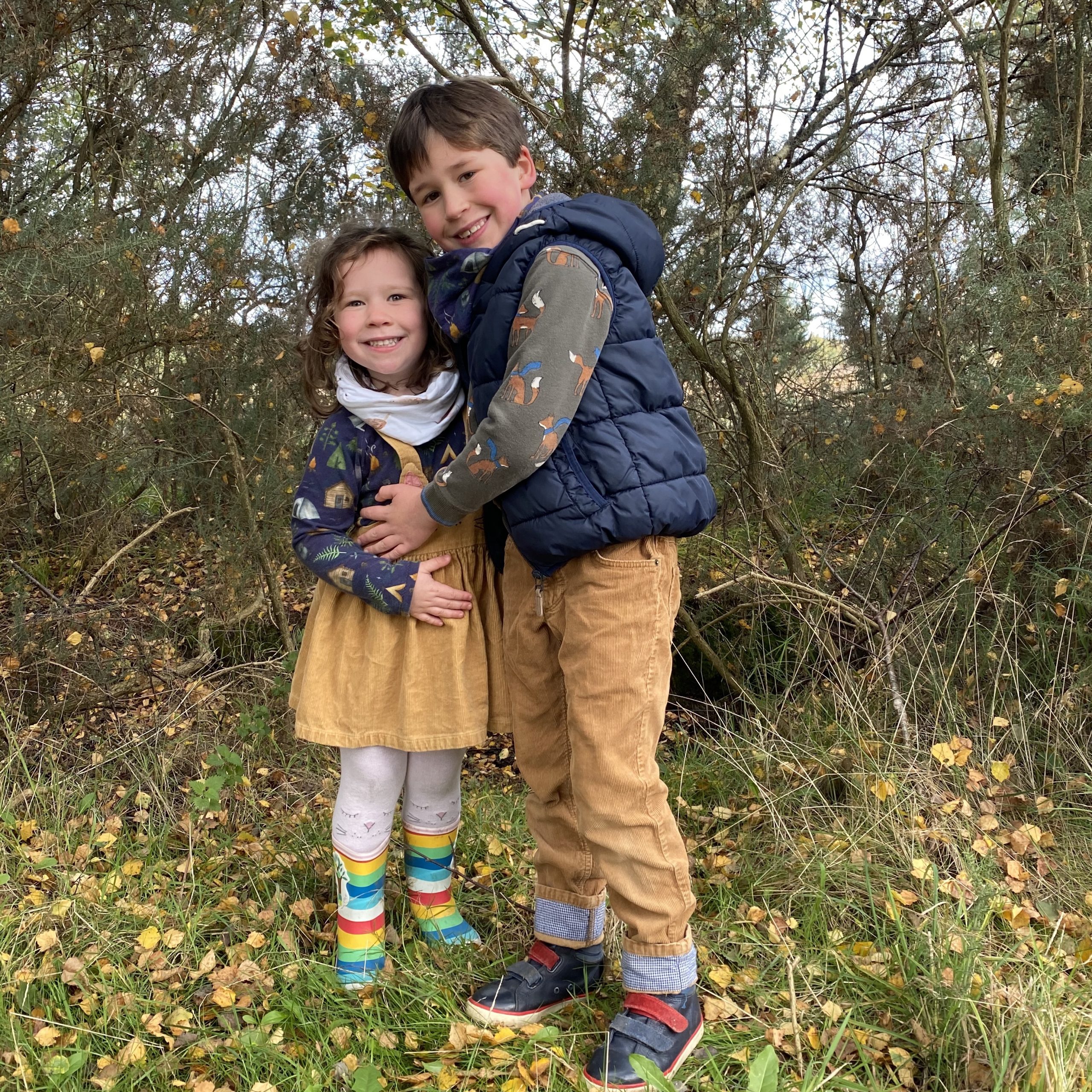 an ordinary week where two children went for a walk and smiled next to teh falling leaves of a tree