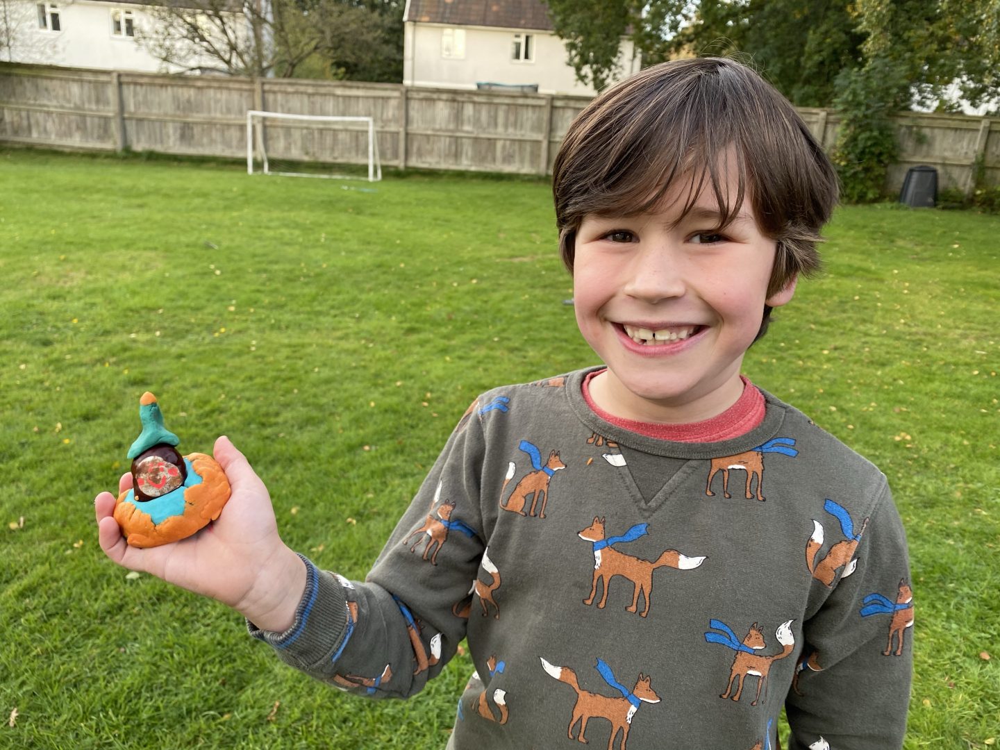 A boy smiling with a playdough conker person 