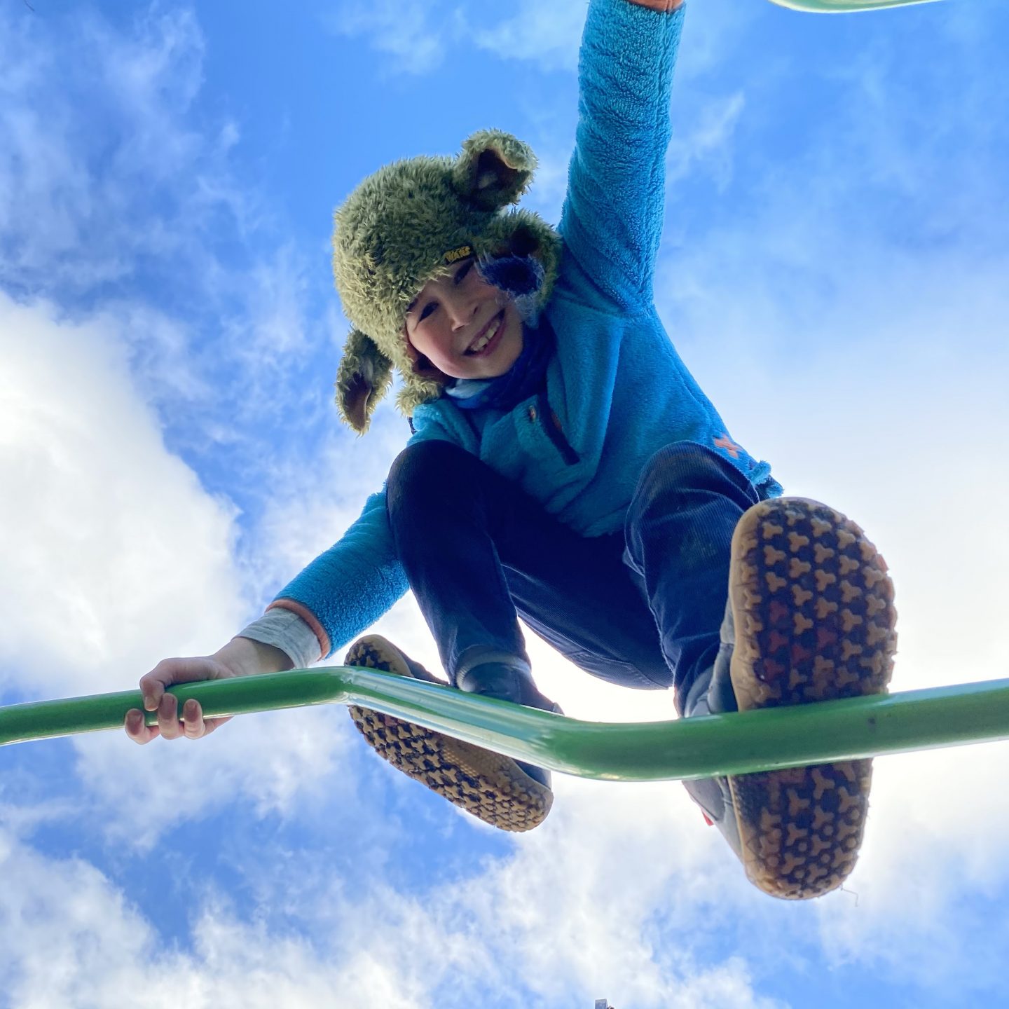 a young boy up a climbing frame smiling 