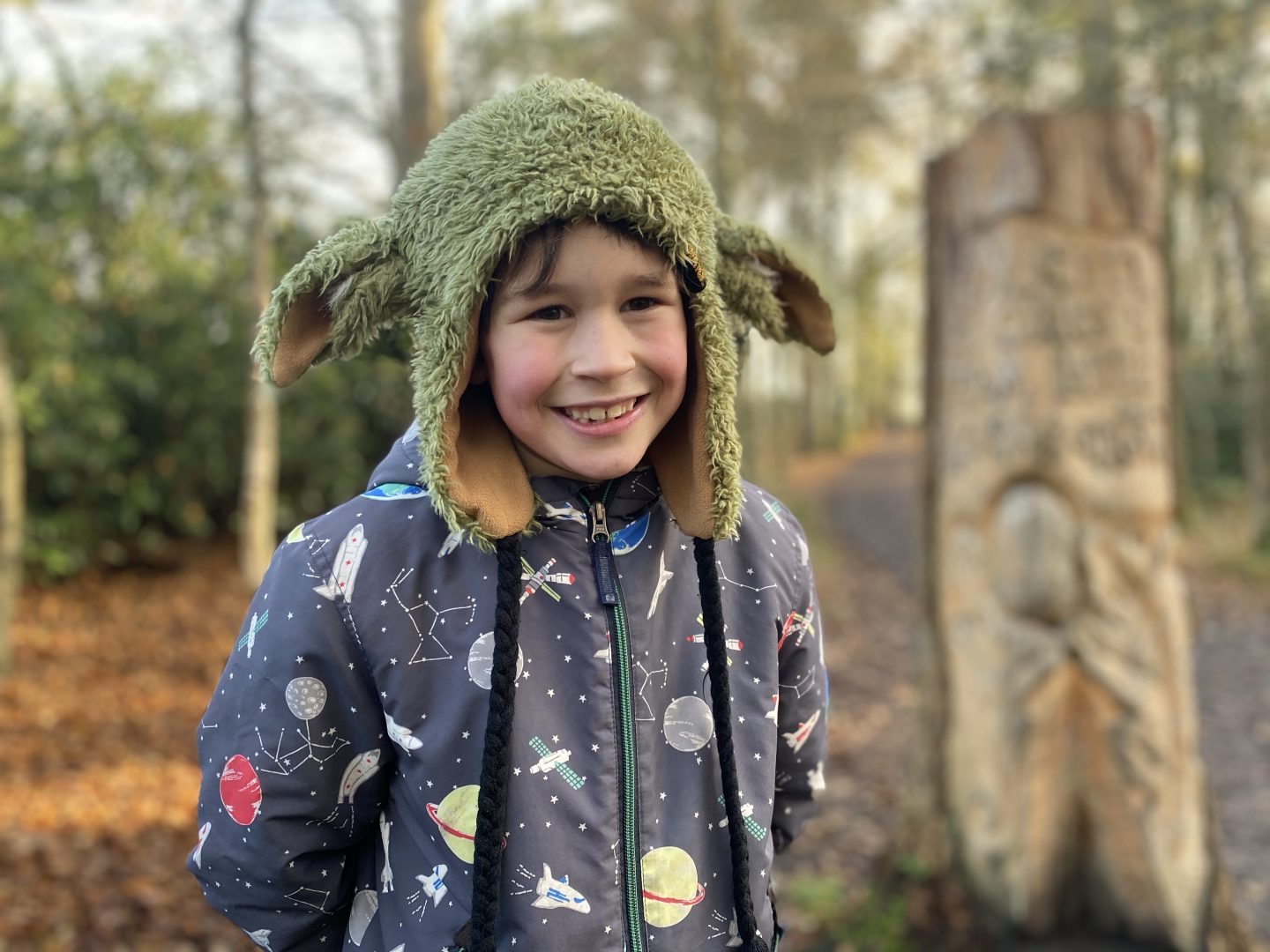 Inset day fun on a woodland walk. A young boy smiling for a picture in the woods