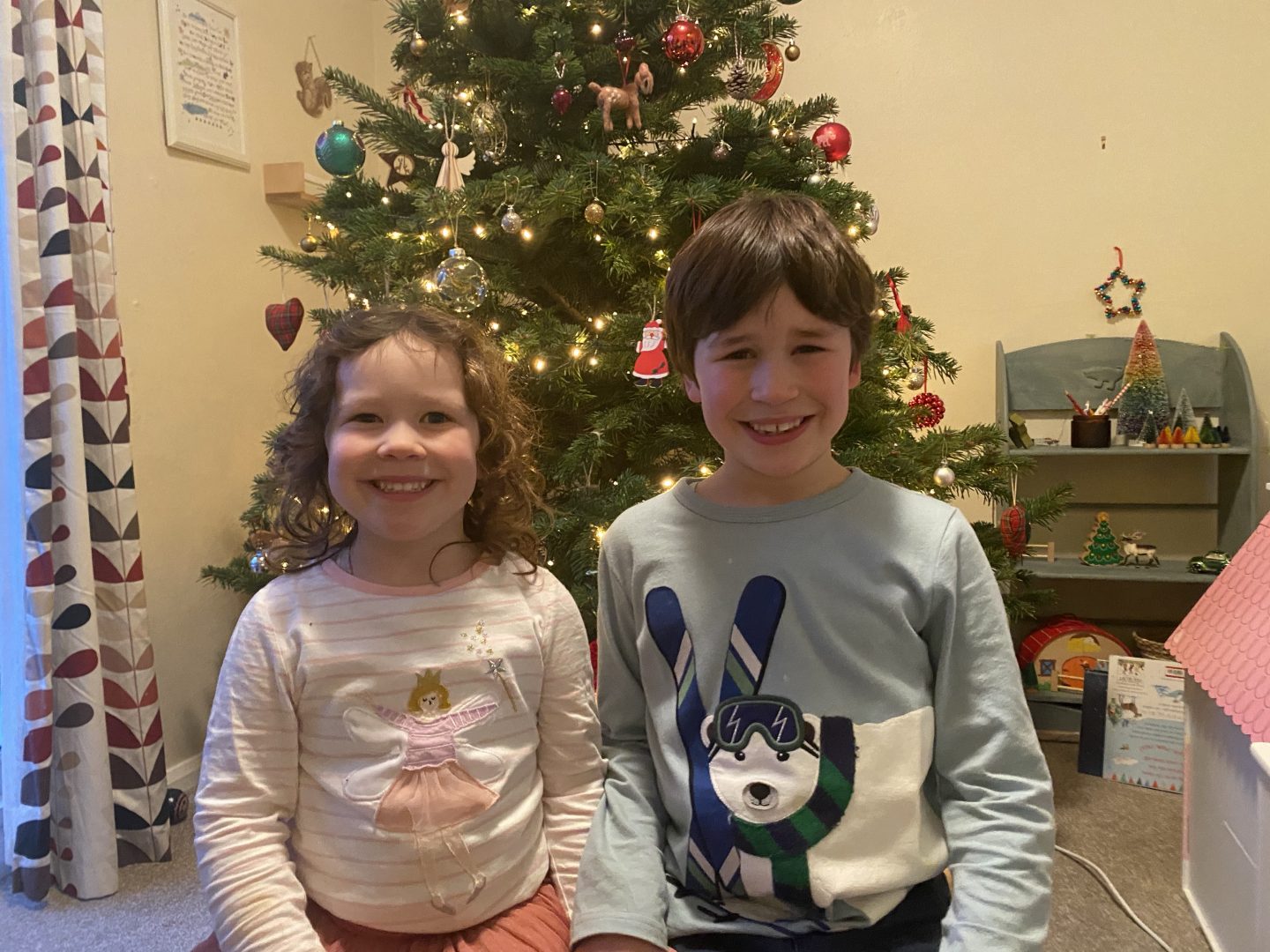 Two children say by the Christmas tree