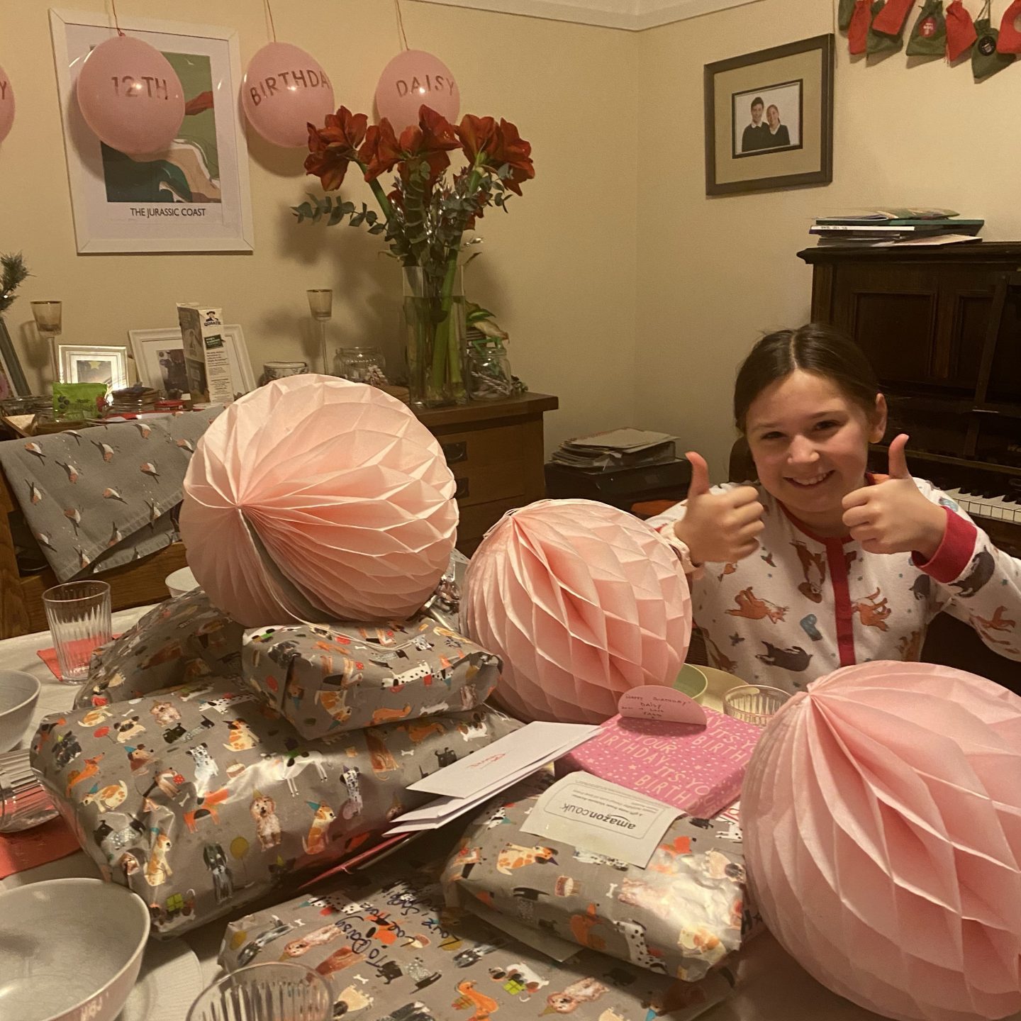 A girl smiling on her Birthday next to presents 