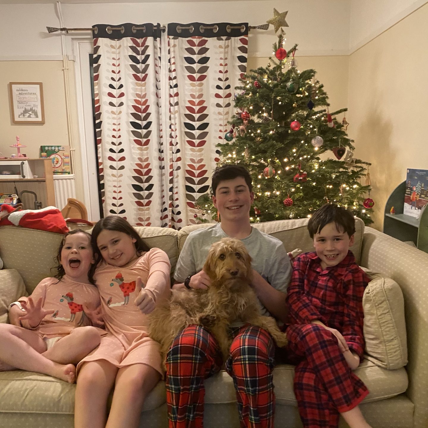 Christmas Eve photo on the sofa with 4  children in pjs smiling 