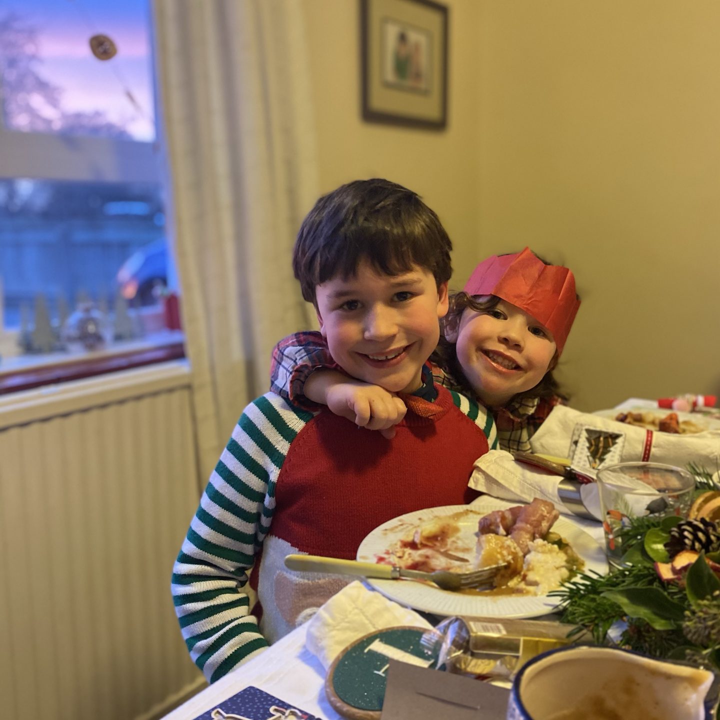 Two children smiling on Christmas   Day with party hats on 
