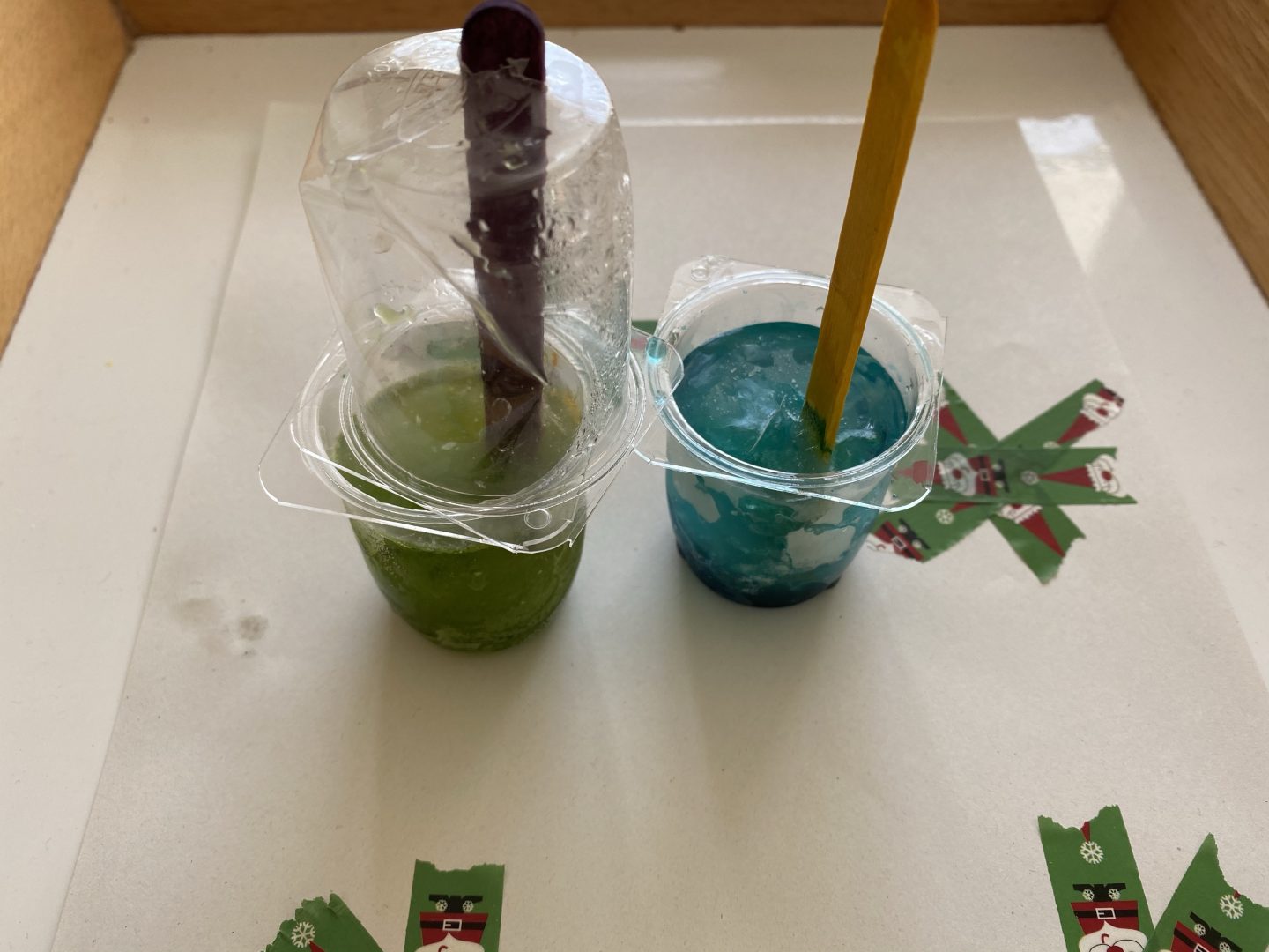 coloured ice cubes set in yoghurt pots with lolly sticks