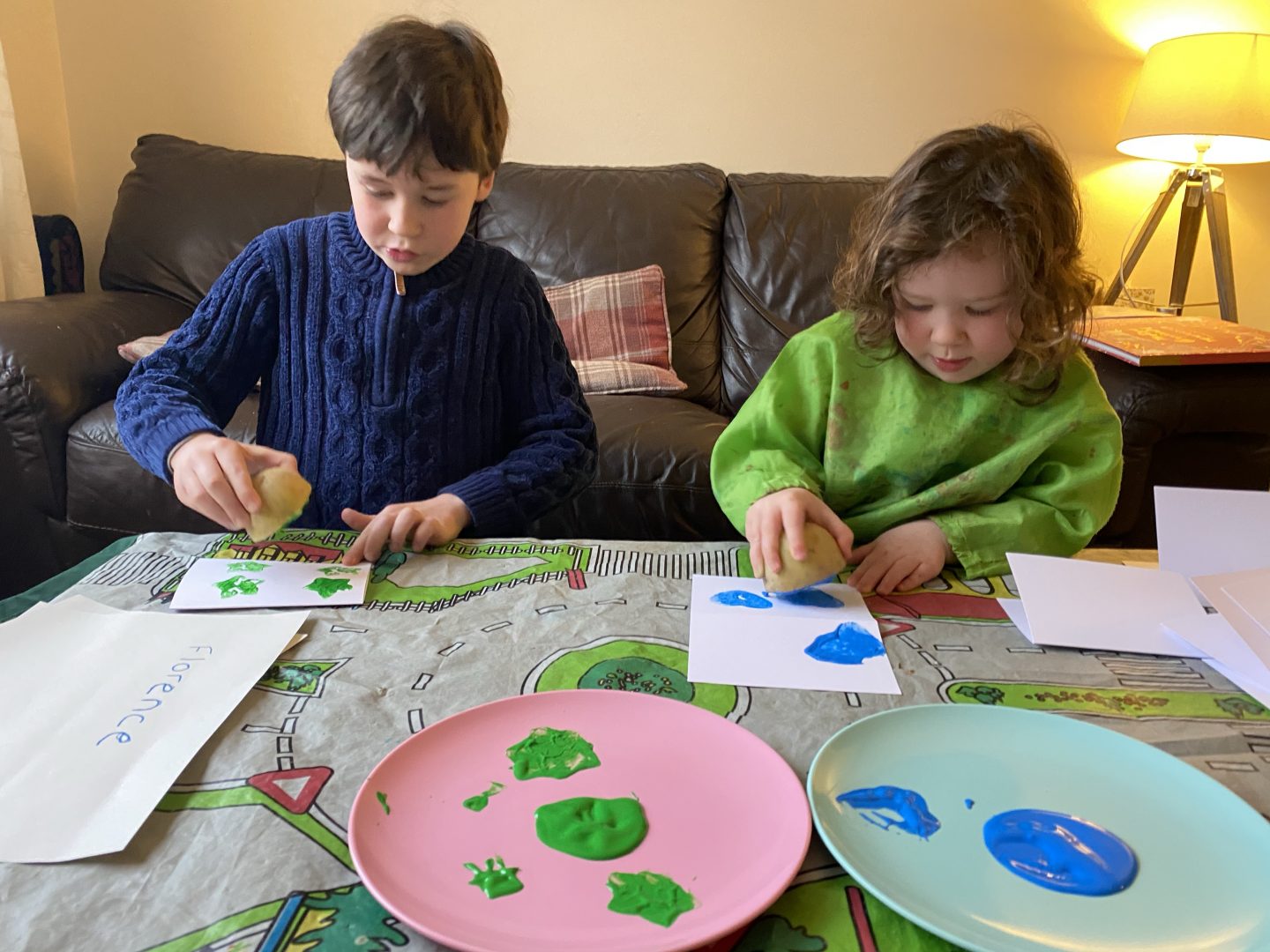 two children painting with potato stamps at a table