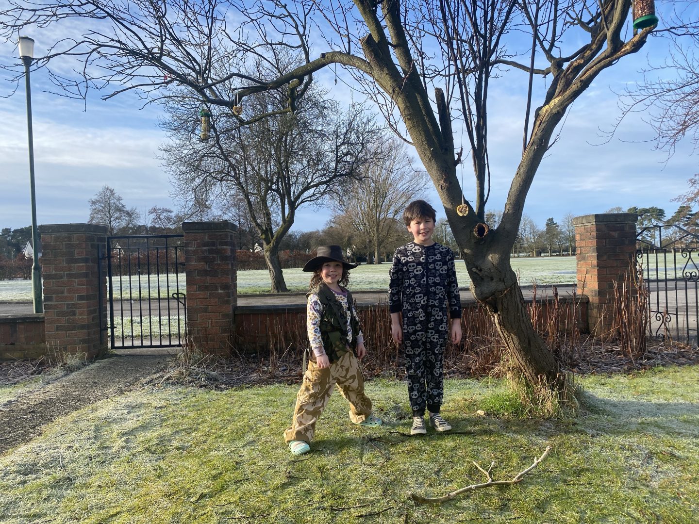 RSPB garden birdwatch with 2 children stood by a tree with bird feeders