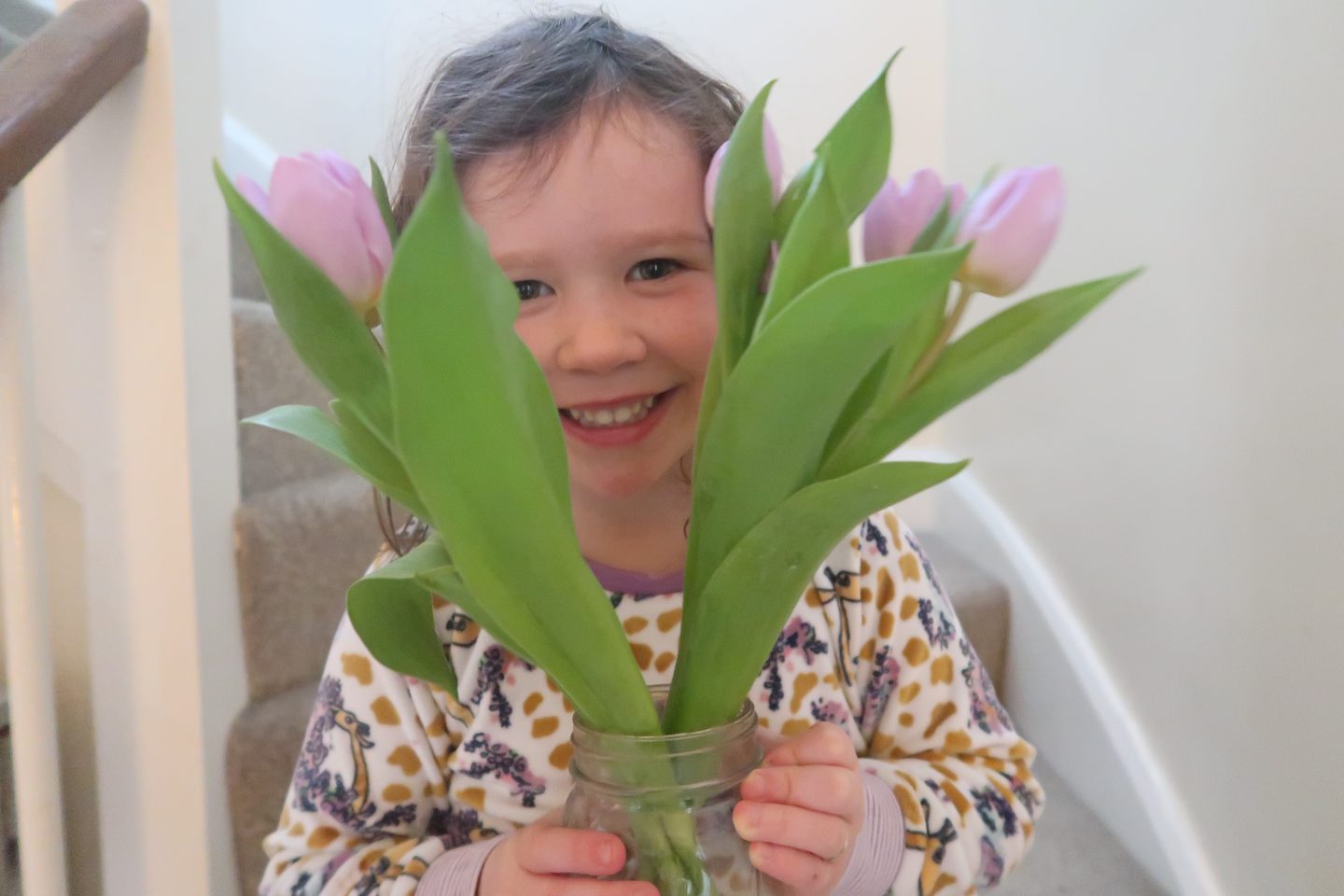 a girl peeking through a vase of flowers on the day the chickens arrived